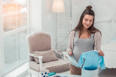 Güzel esmer kadın bebeği için giysi hazırlanıyor