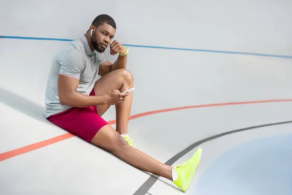 Calm handsome young male athlete with a smartphone — Stock Photo, Image