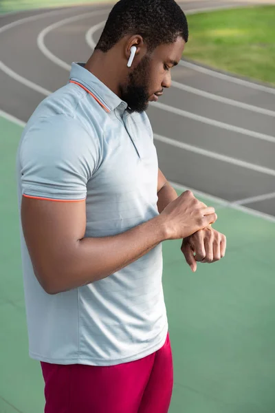 Soustředěný atletický muž pohled na jeho fitness stopaře — Stock fotografie