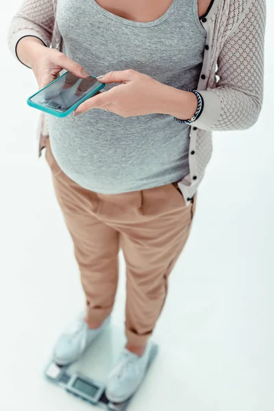 Topp Visa foto av gravid flicka som håller hennes telefon — Stockfoto