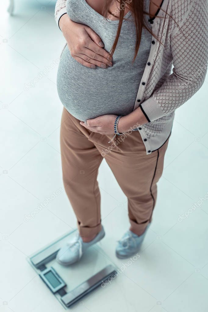 Young pregnant female person standing on weights