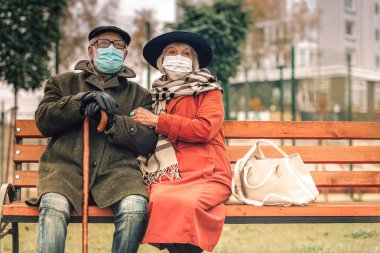 Parkta bankta rahatlatıcı yüz maskeleri ile Hasta yaşlı çift