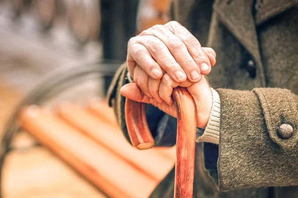 Close up of hands of elderly man leaning on cane — Stock Photo, Image