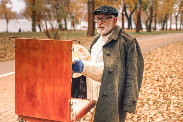 Hombre mayor pintando en el parque otoñal — Foto de Stock