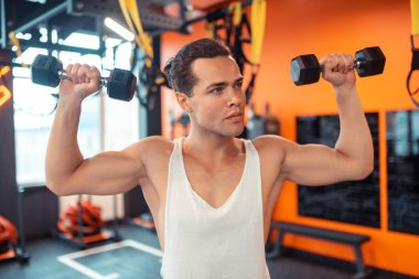 Yakışıklı güçlü adam iki küçük dumbbells tutan