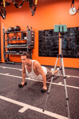 Ciddi çalışkan adam dumbbells ile şınav yapıyor