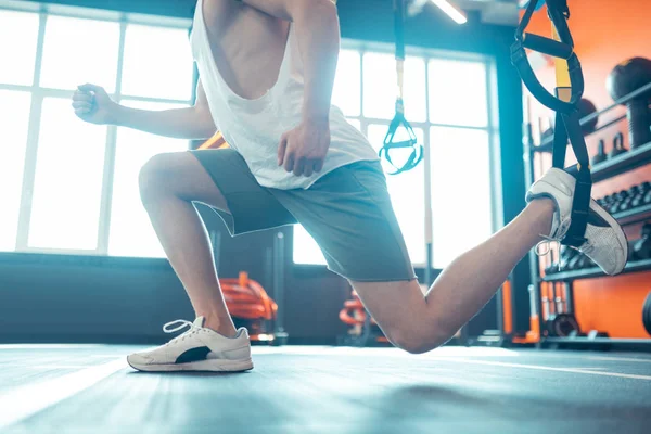 Trx kayışı bacağını koyarak güzel genç adam