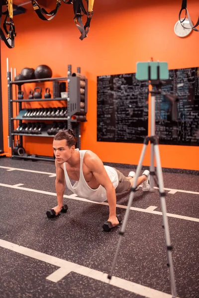 Ciddi çalışkan adam dumbbells ile şınav yapıyor