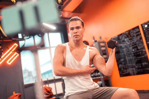 Ciddi iyi görünümlü adam kamera onun kasları gösteren