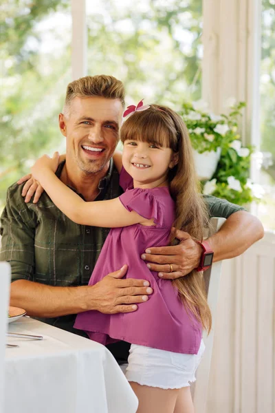 Papà sorridente ampiamente e abbracciando la sua figlia carina — Foto Stock