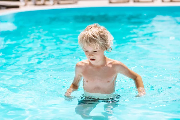 Chico rizado disfrutando del sol y nadando en la piscina — Foto de Stock