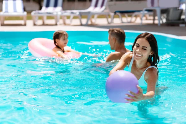 Mamá la captura de la pelota en la piscina mientras se divierten juntos — Foto de Stock