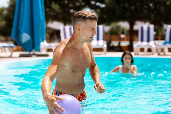 Athlétique beau papa attraper la balle tout en s'amusant dans la piscine — Photo