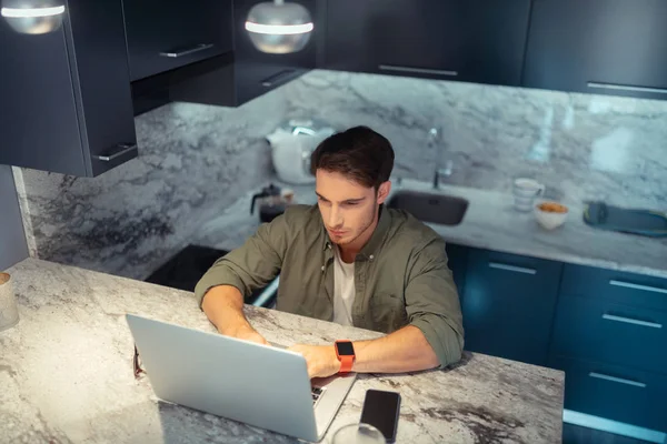 Freelancer vestindo relógio inteligente sentado em casa e trabalhando — Fotografia de Stock