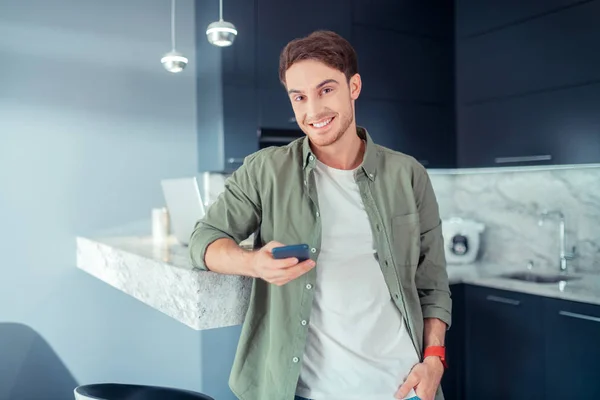 Joven de ojos oscuros sonriendo después de leer el mensaje — Foto de Stock