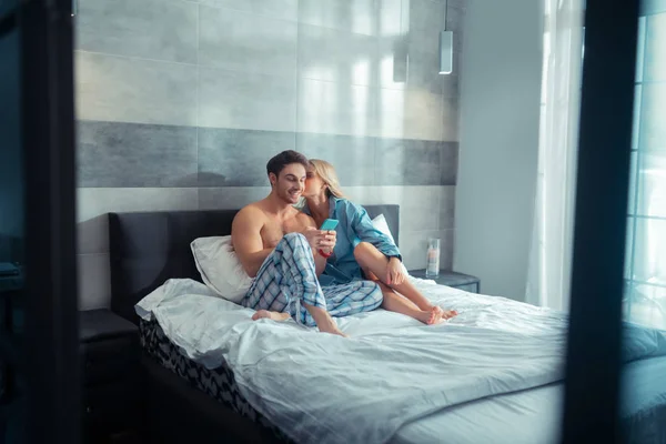 Schöne Freundin küsst ihren Mann, während sie zusammen im Bett liegt — Stockfoto