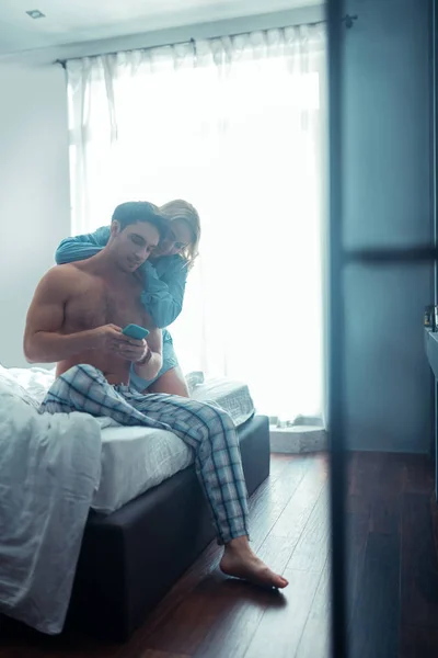 Mann telefoniert, während Freundin ihn umarmt — Stockfoto