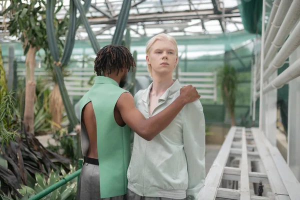 Man wearing open back shirt hugging blonde man — Stock Photo, Image