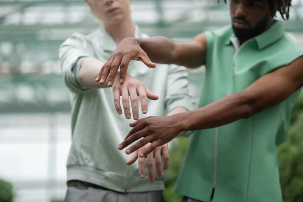 Dark-skinned man and blonde man putting out hands