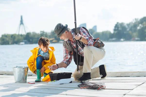 Avô mostrando ganchos de pesca para seu neto — Fotografia de Stock