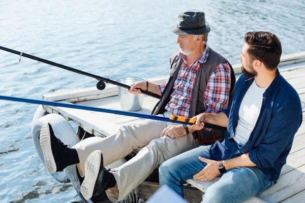 Bearded pensionerad man sitter nära son och fånga fisk — Stockfoto