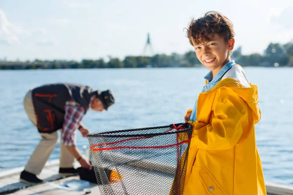 Красивый мальчик улыбается во время рыбалки с дедушкой — стоковое фото