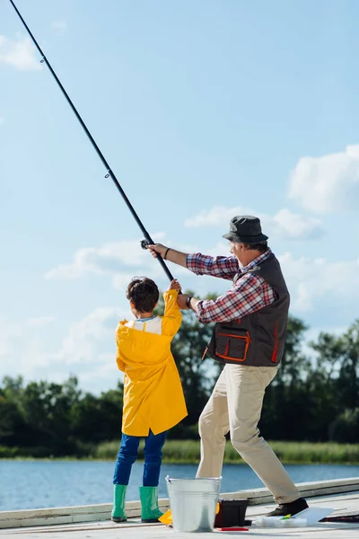 Grandfather and boy pulling fishing tackle while fishing together — Stock Photo, Image