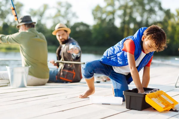 Son looking for hook while having family fishing — Stock Photo, Image