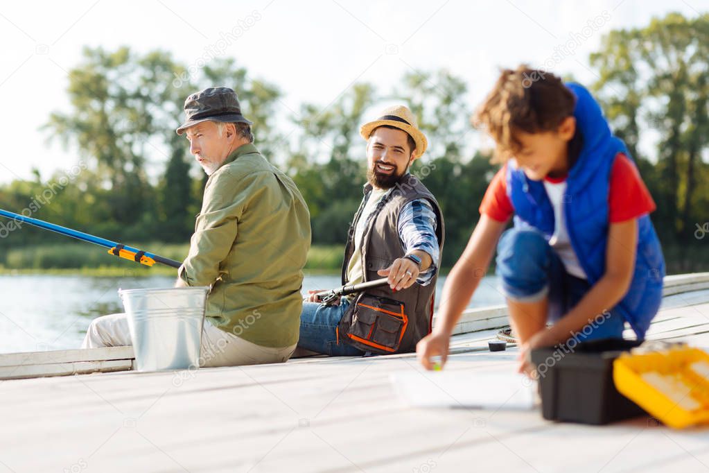 Bearded father asking his son to find fishing hook
