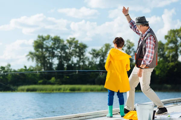 Ragazzo che indossa impermeabile giallo tenendo attrezzatura da pesca — Foto Stock