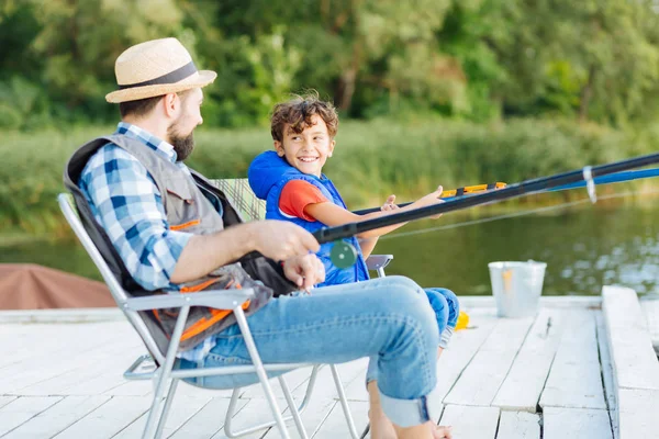 Син дивиться на батька під час риболовлі біля озера — стокове фото