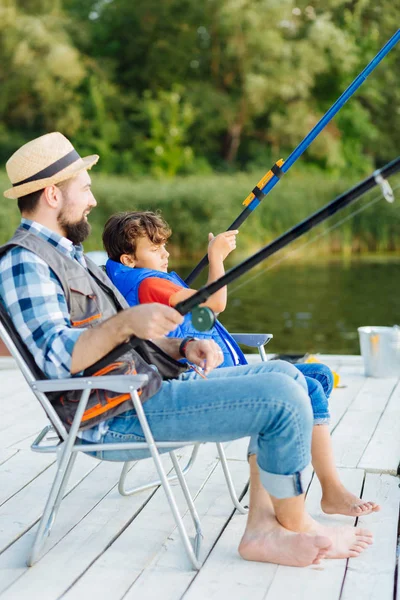 Pai e filho sentado em cadeiras enquanto a pesca na parte da manhã — Fotografia de Stock