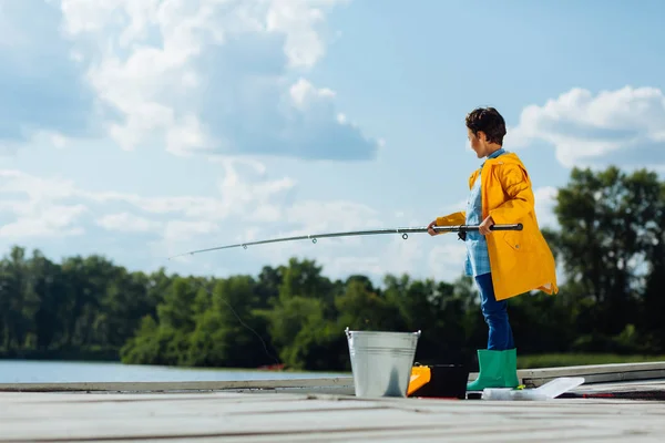 Pojke bär ljust grönt regn stövlar stående och fiske — Stockfoto