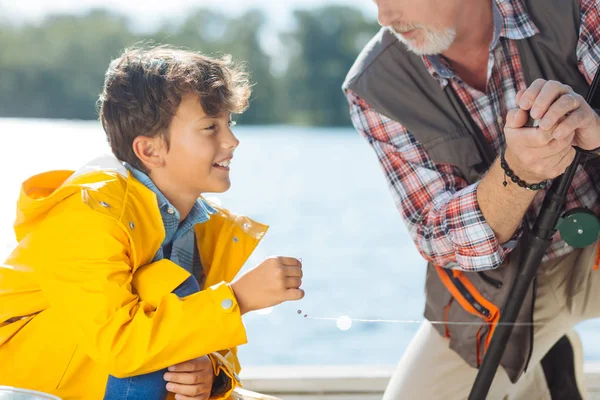 Barbuto nonno dando linea di mare al nipote durante la pesca insieme — Foto Stock