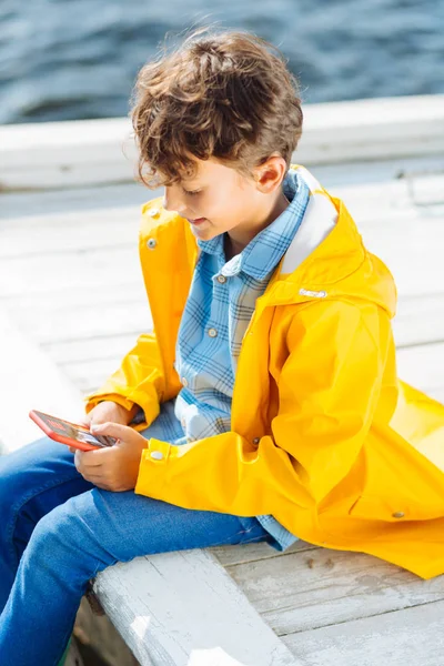 Menino de cabelos escuros jogando jogos em seu smartphone — Fotografia de Stock
