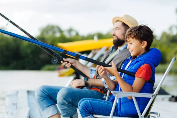Pai e filho segurando pesca aborda enquanto a pesca juntos — Fotografia de Stock