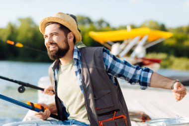 Sakallı koyu saçlı adam babası ile balık tutarken gülümsüyor