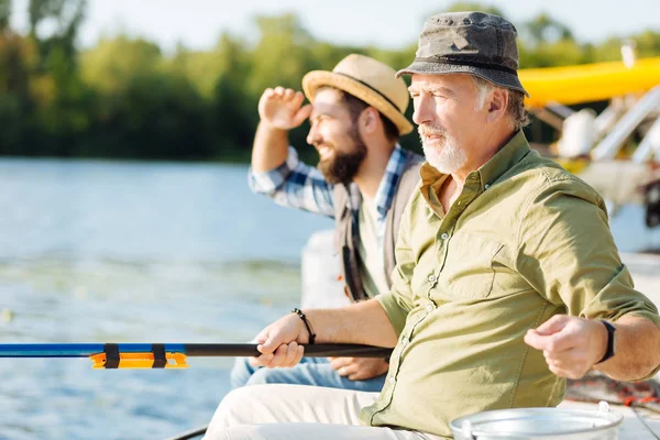胡子退休男子坐在儿子附近钓鱼 — 图库照片