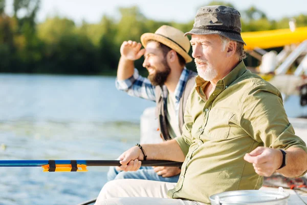 Barbudo jubilado sentado cerca de su hijo y la pesca — Foto de Stock