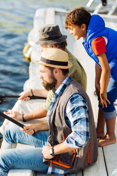 彼の父と祖父の釣りを見て好奇心旺盛な少年 — ストック写真
