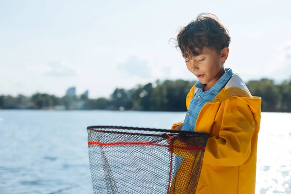 Boy making funny face while looking into fishing net — Stock Photo, Image
