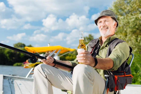 Man smiling while fishing and drinking beer — Stock Photo, Image