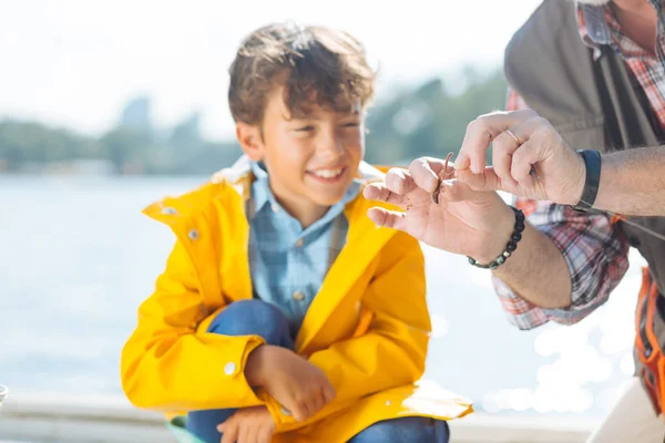 Menino sorrindo enquanto o avô colocando verme no gancho de pesca — Fotografia de Stock