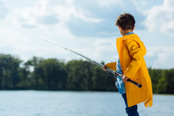 Mörkhåriga skolpojke innehar fiskeredskap och fiske — Stockfoto