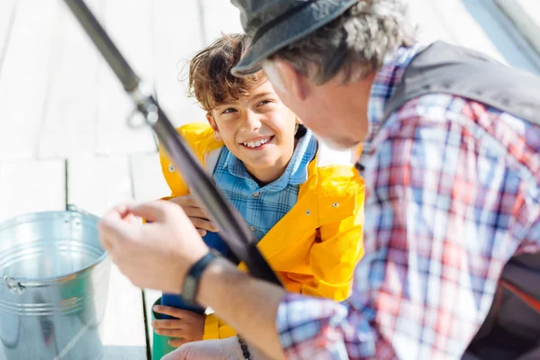 Bello sorridente ragazzo dagli occhi scuri pesca con il nonno — Foto Stock