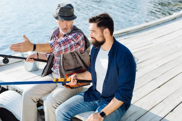 Barbudo hombre de pelo oscuro con elegante reloj de pesca con papá — Foto de Stock