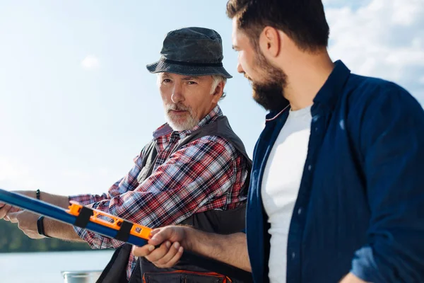 Far och son som håller fiske tacklar samtidigt fånga fisk — Stockfoto