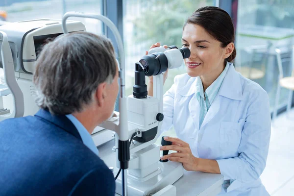 Netter positiver Optiker, der ins Mikroskop schaut — Stockfoto