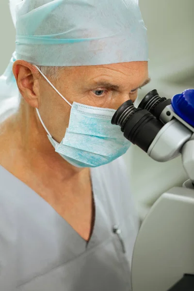 Serious focused man looking into the microscope lenses — Stock Photo, Image