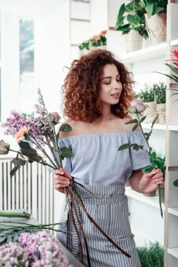 Çiçek demet taşıyan ilham kıvırcık saçlı iyi görünümlü kadın